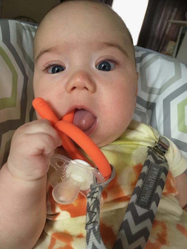 Myron chewing an orange finger-shaped toy