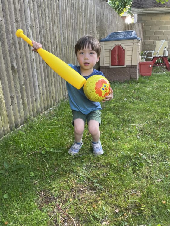 Myron pointing a baseball bat at a soccer ball